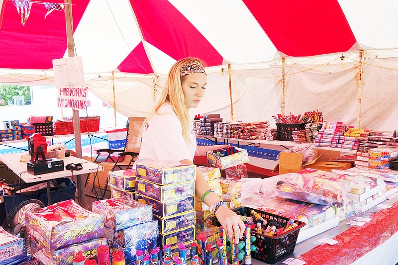 Audrey Jennings inspects her wares at the fireworks booth at the corner of Market and Second streets. She said the Roman candles are especially popular among youths, who "shoot them at each other." What those youngsters might not know is that aside from being dangerous, firing a firework at another person is forbidden by city ordinance.