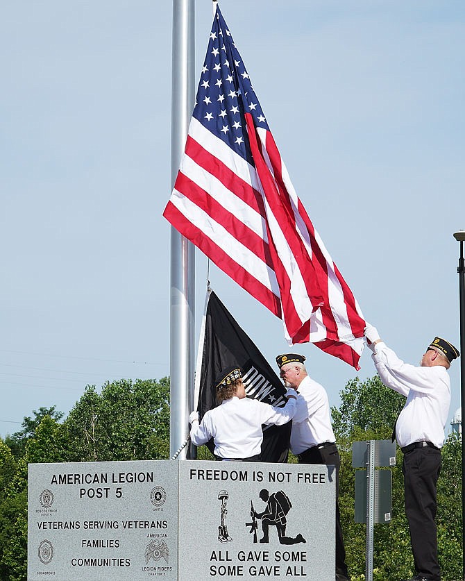 American Legion Post 5's Dee Dee Mehmert-Cryderman, Don Cryderman, right, and Larry Alderson hoist the colors Wednesday morning during a ceremony to dedicate the newly constructed patriotic roundabouts on Jefferson City's east side. One of the roundabouts boasts a bald eagle atop a 6-foot perch of granite. 