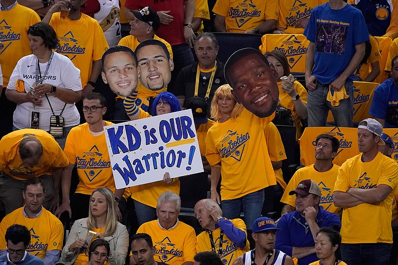 Fans hold up signs for injured Golden State Warriors forward Kevin Durant during the first half of Game 6 of basketball's NBA Finals between the Warriors and the Toronto Raptors in Oakland, Calif., Thursday, June 13, 2019. (AP Photo/Tony Avelar)