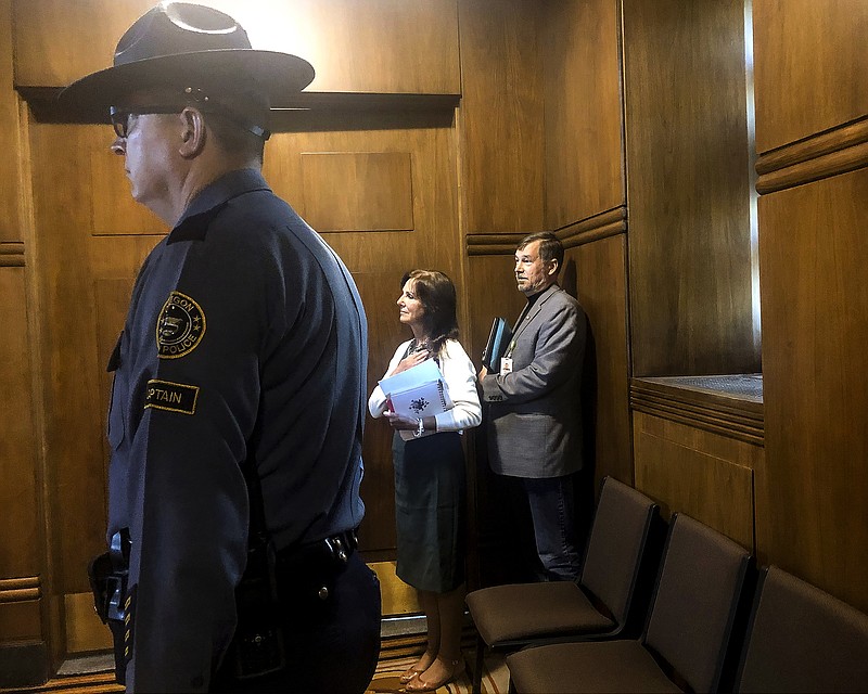 An Oregon state trooper stands guard as Oregon State Republican Sen. Brian Boquist waits with his wife,Peggy Boquist, to walk onto the Senate floor Sunday, June 30, 2019 in Salem, Ore. Sen. Democratic Sen. Shemia Fagan said Sunday that some Democrats are demanding Republican Sen. Brian Boquist not be allowed to return to the floor. Boquist drew criticism for saying police should "come heavily armed" if they tried to return him to the Capitol amid a GOP walkout over climate legislation. (AP Photo/Sarah Zimmerman)