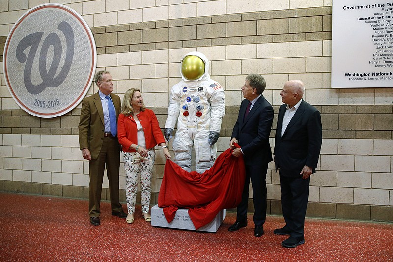 FILE - In this June 4, 2019 file photo, Washington Nationals senior vice president Gregory McCarthy, from left, Ellen Stofan of the National Air and Space Museum, statue donor Allan Holt and Nationals owner Mark Lerner unveil a statue of Neil Armstrong's Apollo 11 spacesuit before an interleague baseball game between the Chicago White Sox and the Nationals in Washington. It was unveiled as part of the "Apollo at the Park" program, which will place statues of Armstrong's spacesuit at ballparks across the country to commemorate the moon landing's 50th anniversary. (AP Photo/Patrick Semansky)