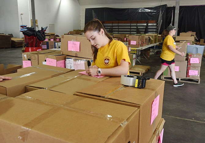 Sisters Cassie, foreground, and Annie Pruitt volunteer their time and services at the Seventh Day Adventist Distribution Center at Capital West Event Center. They've been involved since the beginning when donated items started coming in. Items delivered range from toothbrushes to kitchen utensils to mattresses and mirrors and much, much more. The items are repackaged for easy access when clients come in to fill out a "shopping list" of sorts. 