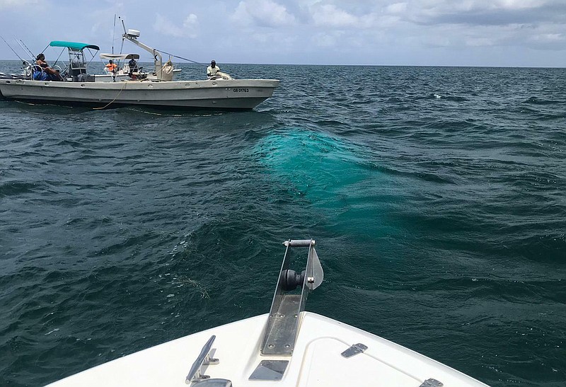 In this handout photo provided by the Bahamas ZNS Network, a recovery team stands by at the wreckage site where a helicopter carrying four women and three men, including billionaire coal entrepreneur Chris Cline and his daughter,     crashed outside a string of islands Cline owned in the Bahamas, Friday, July 5, 2019. The bodies of the four women and three men were recovered and taken to the Bahamian capital of Nassau to be officially identified. (Krystel Knowles/Bahamas ZNS Network via AP)