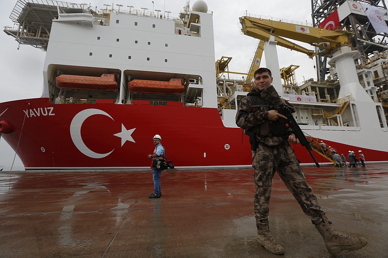 FILE - In this Thursday, June 20, 2019 file photo, a Turkish police officer patrols the dock, backdropped by the drilling ship 'Yavuz' scheduled to be dispatched to the Mediterranean, at the port of Dilovasi, outside Istanbul. Cyprus is condemning a second attempt by Turkey to drill for gas in waters off its coast as an escalation in its breach of international law. (AP Photo/Lefteris Pitarakis, File)