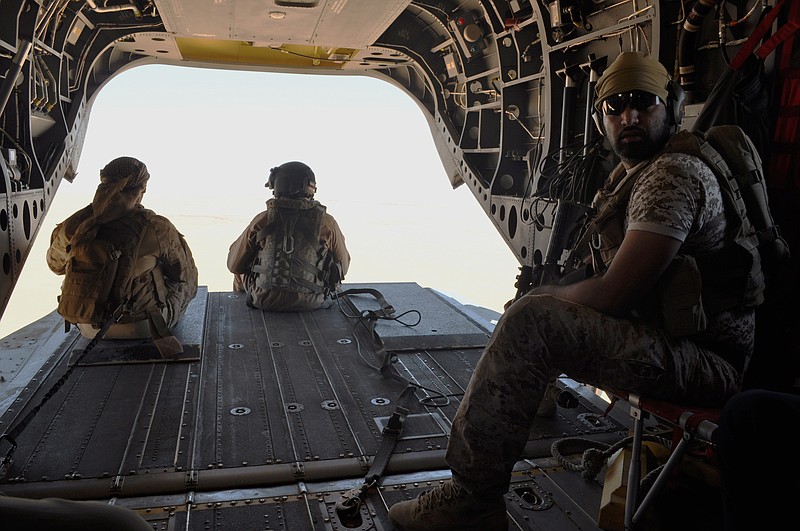 FILE - In this Sept. 14, 2015, file photo, Emirati soldiers stand guard out the rear gate of a Chinook military helicopter traveling from Saudi Arabia to Yemen. The United Arab Emirates has drawn down the number of its troops in Yemen, but has not withdrawn from the country and remains a key member of the Saudi-led coalition at war there, a senior Emirati official confirmed Monday, July 8,2 019. The official declined to give figures on how many troops have been withdrawn or how many remain in Yemen, but said the UAE remains committed to the Saudi-led coalition there. (AP Photo/Adam Schreck, File)