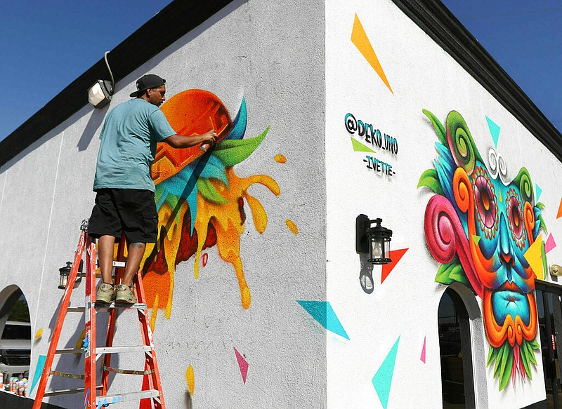 Muralist Benito Mendoza, aka Deko_Uno, paints a mural of a burger on the north side of Curb Side Bistro Tuesday, May 28, 2019 in Odessa, Texas. Mendoza grew up in a dangerous neighborhood of Juarez, Mexico, where gang activity and graffiti go hand in hand. While most people in his neighborhood would use spray cans to mark their territory Mendoza was inspired by the power it had as a social purpose. Mendoza said he was highly influenced by the 20th century Mexican painter Diego Rivera. Rivera set an example as a community activist who painted the working class and helped establish the Mexican mural movement through his public murals. (Jacob Ford/Odessa American via AP)