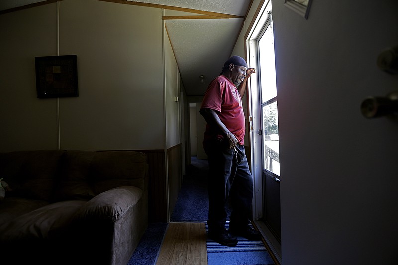 In this photo taken Wednesday, May 29, 2019, resident James Lesane stands at the entrance to his mobile home in Lumberton, N.C. Every month, Lesane pays what he can afford for his mobile home lot rental; $150. But, after the Florida-based company Time Out Communities bought the park, he got a notice in the beginning of this year that his lot rent would be increasing to $465 a month. Mobile home residents in Robeson County, North Carolina are seeing increasing rent prices after being slammed by hurricanes Matthew and Florence.(AP Photo/Gerry Broome)