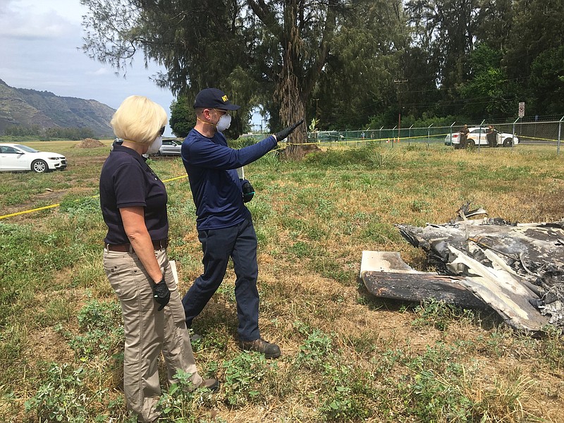 FILE - This Sunday, June 23, 2019 file photo released by the National Transportation Safety Board shows NTSB investigator Eliott Simpson briefing NTSB Board Member Jennifer Homendy at the scene of the Hawaii skydiving crash near Waialua, Hawaii on Oahu's North Shore. The National Transportation Safety Board says a witness to the crash that killed 11 people reported the plane's engines sounded normal before takeoff, but shortly after the plane left the ground it became inverted and crashed nose down. The NTSB's preliminary report was released Tuesday, July 9, 2019. No cause for the crash was given, which is typical for preliminary reports. (National Transportation Safety Board via AP, File)