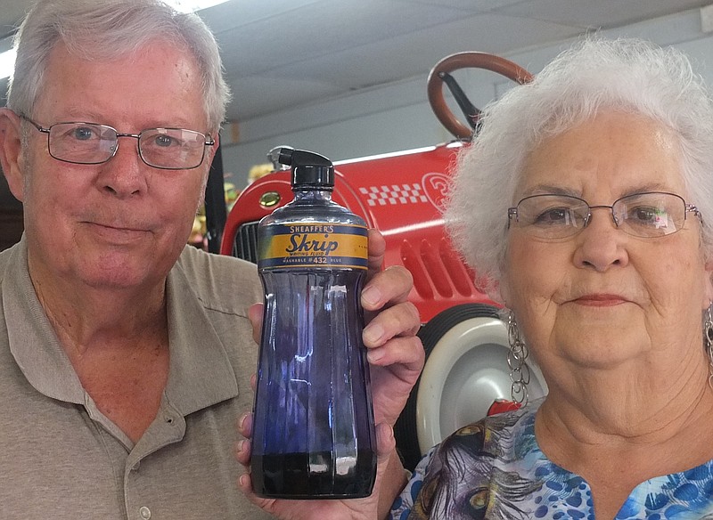 Here's a mystery. Mike Helms and Janice Parks are holding a rare, old-time container. Do you remember the Shaeffer fountain pen and Skrip blue ink required to fill it? Have one? Well, if you do, come down to their Ark La Tex Enterprises store for an ink pen refill from this Sheaffer's Writing Fluid original bottle.

