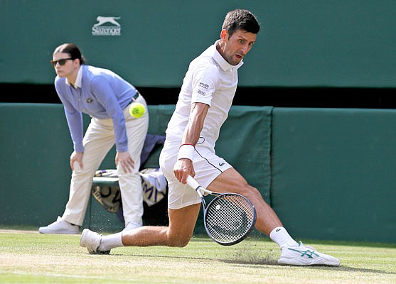 Novak Djokovic slides while returning the ball to Ugo Humbert during their singles match Monday at Wimbledon in London.