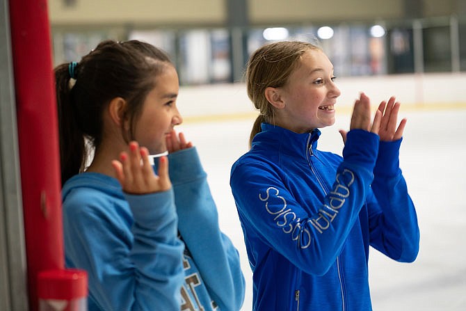 Brownleigh Collier, left, and Abigail Bruce, both 12, clap for their friend Jessi Johnson as she practices some skating tricks on the ice Wednesday at Washington Park Ice Arena.
