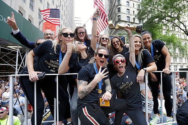 Megan Rapinoe holds the Women's World Cup trophy as the U.S. women's soccer team is celebrated Wednesday with a parade along the Canyon of Heroes in New York.
