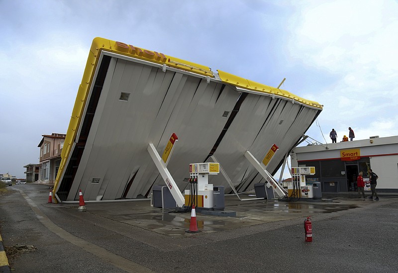 Workers check the damages at a gas station after a storm at Nea Potidea village in Halkidiki region, northern Greece, Thursday, July 11, 2019. A search and rescue operation is underway in northern Greece for a fisherman missing after a powerful storm left six people dead, including two children, and injured more than 100. (Giannis Moisiadis/InTime News via AP)