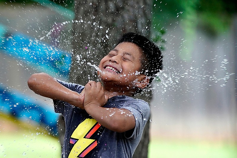 Byron Xol, an immigrant from Guatemala, squeezes a water balloon during his birthday party Sunday, June 23, 2019, in Buda, Texas. "Super good!" the 9-year-old yelled, again and again as they burst. (AP Photo/David J. Phillip)