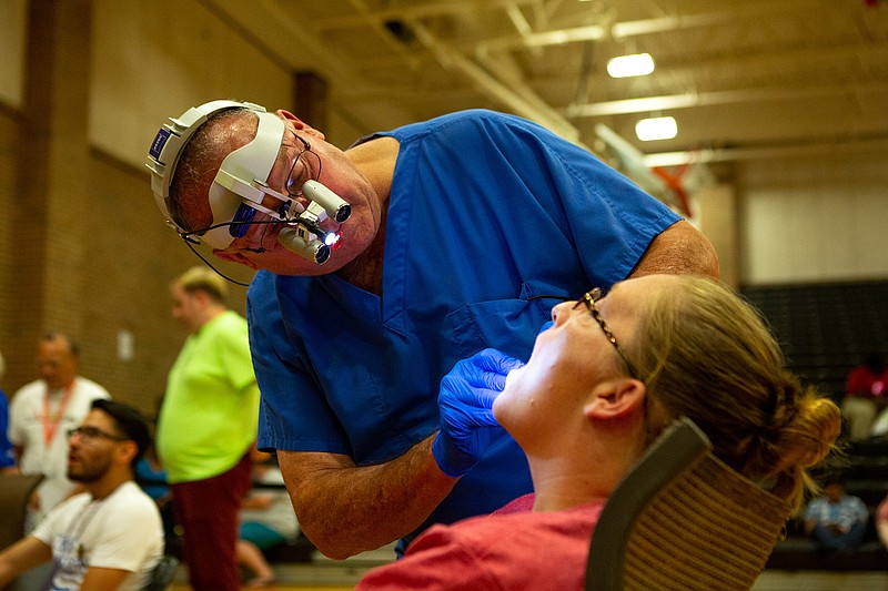 Dr. Milburn Haynes examines Teresa Hanson's teeth Friday at Texas Mission of Mercy Dental Clinic at Texas High School. CHRISTUS St. Michael Health System partnered with Texas Dental Association Smiles Foundation to host the Texas Mission of Mercy Mobile Dental Clinic, which provides the underserved with dental care at no cost.