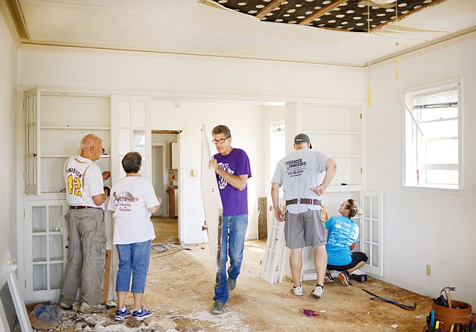 Volunteers work to remove doors and built-in cabinets Saturday during an architectural salvage project. The home, located on Jackson Street, is scheduled to be demolished after it was damaged in the May 22 tornado. The Historic City of Jefferson is managing the project to save historical features such as doors, wood trims and lighting to be repurposed.