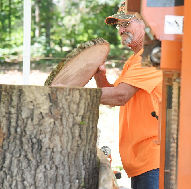 Keith Olsen demonstrates the process he'll use to make wooden plaques from tornado-damaged trees that will be presented to volunteers at the Redemption Inside the Walls concert in August. 