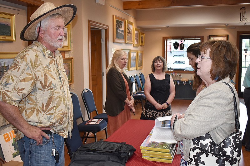 Billyo O'Donnell, left, chats with Faye Zumwalt on Sunday at Capital Arts. O'Donnell, an artist, and writer Karen Glines (background, left) held a book signing for their book, "Painting Missouri."