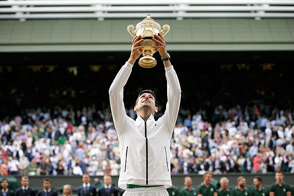 Novak Djokovic lifts the trophy after defeating Roger Federer in Sunday's men's singles final match of the Wimbledon Championships in London.