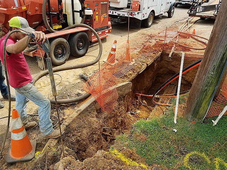 A contractor working for Windstream overlooks a hole where a telephone cable is being repaired Tuesday, July 16, 2019, at East Fifth and Ash streets in Texarkana, Ark. On July 9, a Southwest Arkansas Telephone Cooperative crew accidentally cut the cable, stopping landline phone service for about 400 Windstream customers.