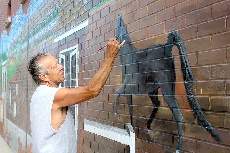 Muralist Dennis Holliday prepares to make the final brushes to complete one of the two horses on the Moniteau County Fair mural July 15, 2019.