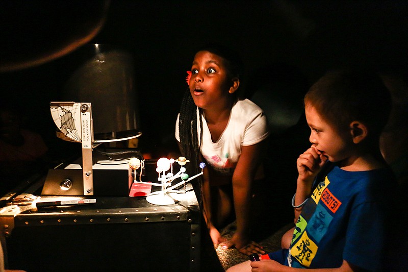 London Smith, 8, and Luke White, 5, look at a model of the solar system Tuesday during the Space Odyssey program at the Texarkana Public Library.
