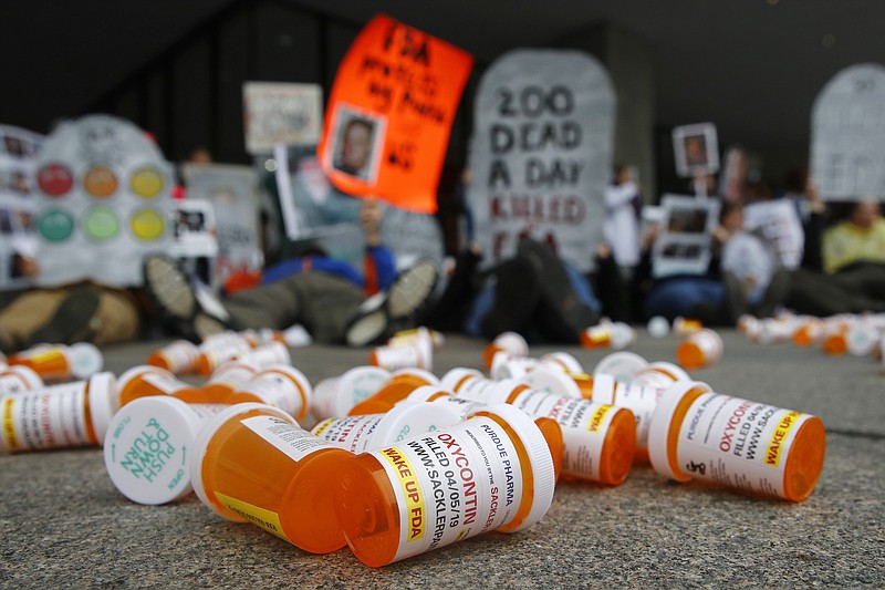 FILE - In this April 5, 2019, file photo, containers depicting OxyContin prescription pill bottles lie on the ground in front of the Department of Health and Human Services' headquarters in Washington as protesters demonstrate against the FDA's opioid prescription drug approval practices. (AP Photo/Patrick Semansky, File)