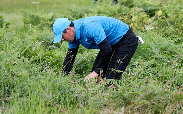 Rory McIlroy looks for his ball in the long rough on the first hole during Thursday's first round of the British Open at Royal Portrush in Northern Ireland.