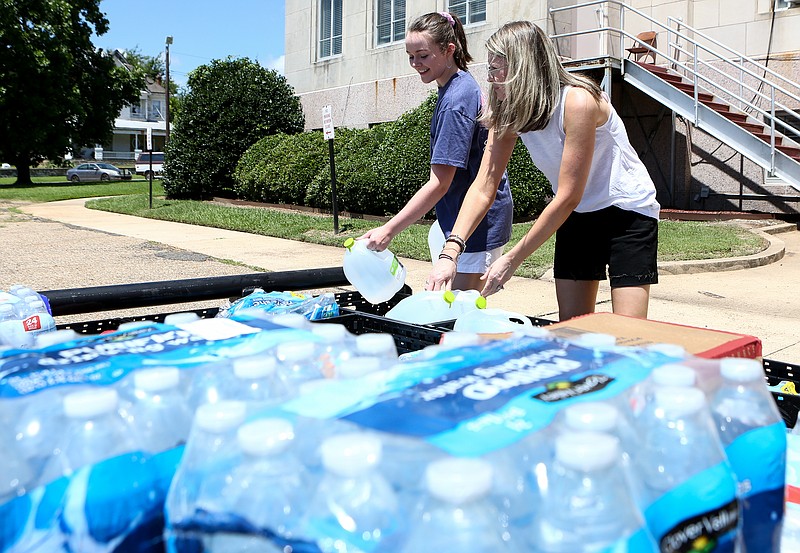 Sancha Pendergraft and her daughter, Gracie, place jugs of water in a trailer at Miller County Courthouse on Friday, July 20, 2019, in Texarkana, Arkansas. The water drive at the courthouse is for residents of Dierks, many of whom are without running water.