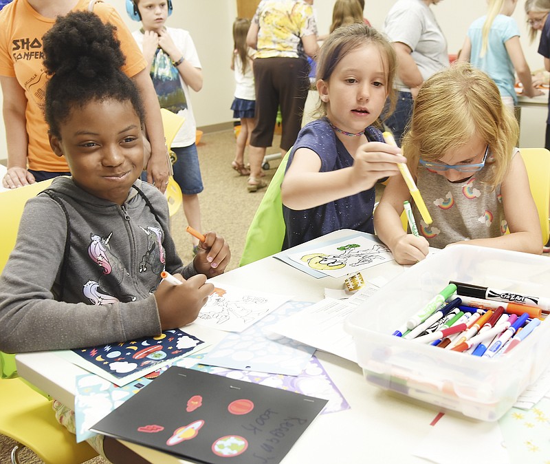 Julie Smith/News Tribune
Alexis Seeney, 8, at left, and Lily Cornine, 7, middle, both from A Place to Grow in Holts Summit, join Morgan Sisk, 9, at right, to color in printed drawings as they take part in activities at the Holts Summit Public Library. Parents, grandparents and daycares brought dozens of youngsters to the library Wednesday for the Magic School Bus Celebration during which children colored drawings, made crafts and dabbled in science experiments. They were encouraged to take chances, make mistakes and get messy while participating in the fun. 