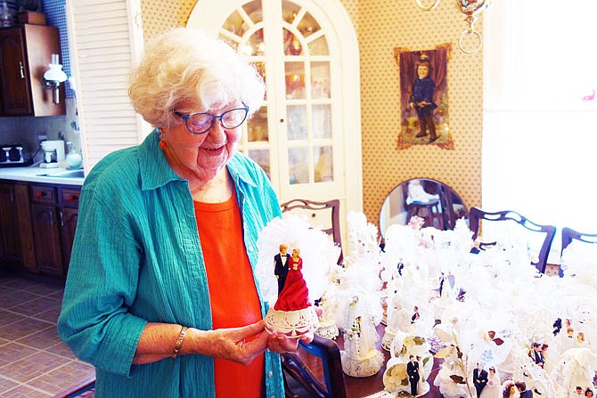 Barbara Binger holds one of the more colorful vintage wedding cake toppers in her collection. Red dresses are a wedding custom in some Asian nations, she explained.