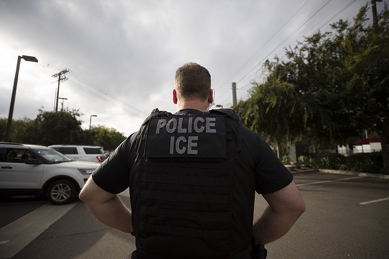 FILE - In this July 8, 2019, file photo, a U.S. Immigration and Customs Enforcement (ICE) officer looks on during an operation in Escondido, Calif. Advocacy groups and unions are pressuring Marriott, MGM and others not to house migrants who have been arrested by U.S. Immigration and Customs Enforcement agents. But the U.S. government says it sometimes needs bed space, and if hotels don’t help it might have to split up families. (AP Photo/Gregory Bull, File)