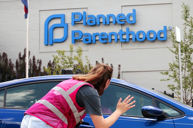 FILE - In this June 28, 2019 file photo, Ashlyn Myers of the Coalition for Life St. Louis, waves to a Planned Parenthood staff member in St. Louis, Mo. (Robert Cohen/St. Louis Post-Dispatch via AP)