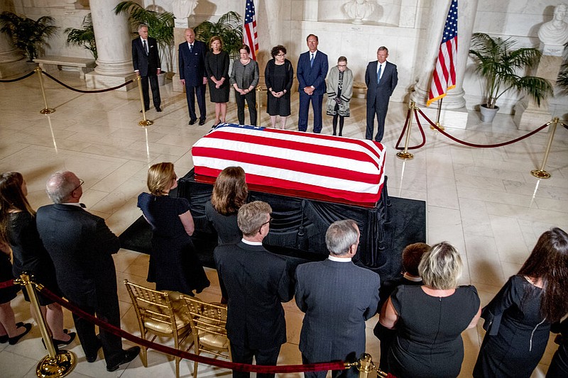 From center left, retired Associate Justice Anthony Kennedy, Ashley Kavanaugh, the wife of Associate Justice Brett Kavanaugh, Associate Justice Elena Kagan, Associate Justice Sonia Sotomayor, Associate Justice Samuel Alito, Associate Justice Ruth Bader Ginsburg, and Chief Justice John Roberts participates in a ceremony along with family, below, for the late Supreme Court Justice John Paul Stevens as he lies in repose in the Great Hall of the Supreme Court in Washington, Monday, July 22, 2019. 