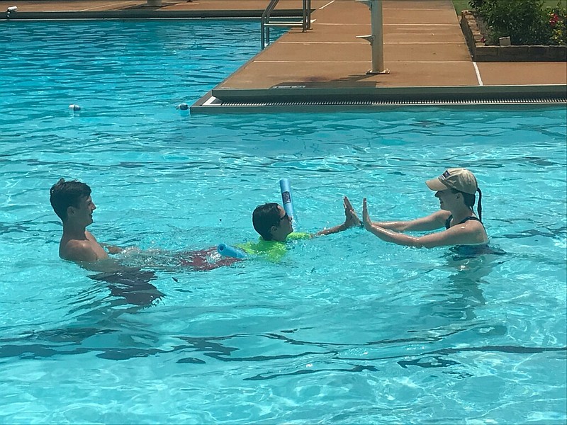 Oakley Ward gets help learning to swim from volunteers Layton Lammers and Sophia Zaeringer at the Texarkana Country Club Monday afternoon.