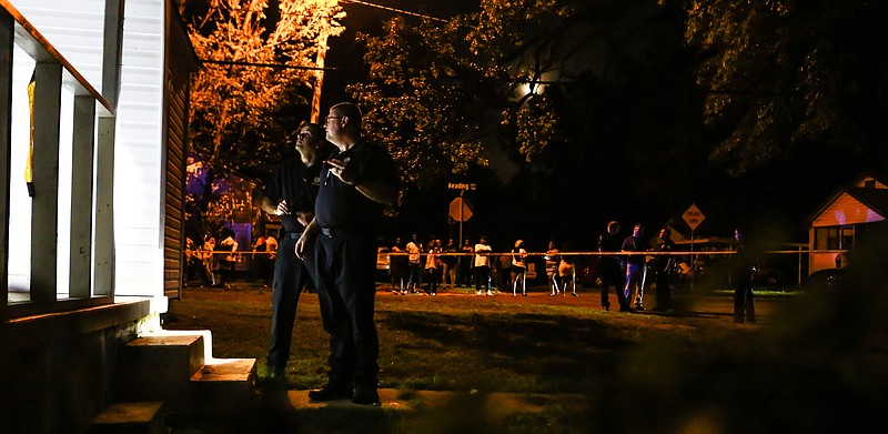 Texarkana, Texas police officers investigate the crime scene of a double homicide that occurred late into the night while members of the community stand and watch on Sunday, July 21, 2019, in Texarkana, Texas. The crime scene was on the 200th block of Connelly Street that drew out a large crowd from the neighborhood. The victims of the homicide were shot multiple times and found dead inside of the building.