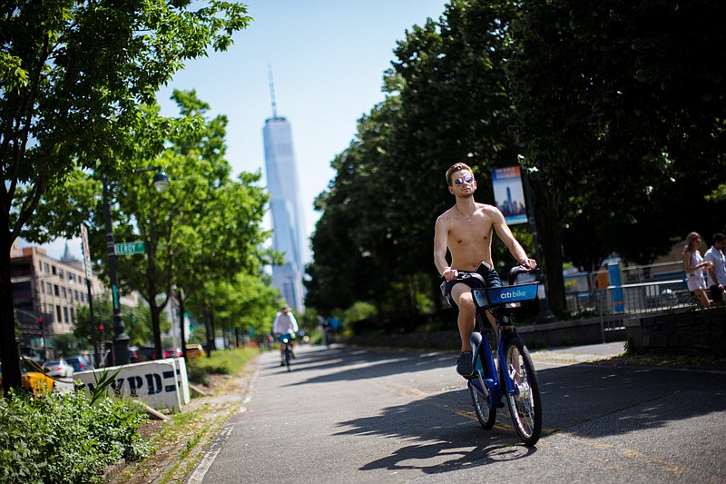 Cyclists ride down a path near the Hudson River during high temperatures on Saturday, July 20, 2019 in New York. Temperatures in the high 90s are forecast for Saturday and Sunday with a heat index well over 100. Much of the nation is also dealing with high heat. One World Trade Center is seen in the background. (AP Photo/Eduardo Munoz Alvarez)