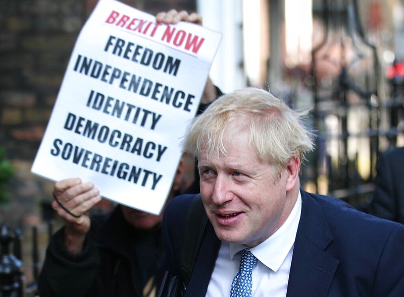 Conservative party leadership contender Boris Johnson, is shadowed by a Brexit demonstrator, as he arrives at his office in central London, Tuesday July 23, 2019. Britain's governing Conservative Party is set to reveal the name of the country's next prime minister later Tuesday, with Brexit champion Boris Johnson widely considered to be favourite to get the job against fellow contender Jeremy Hunt. (Yui Mok/PA via AP)