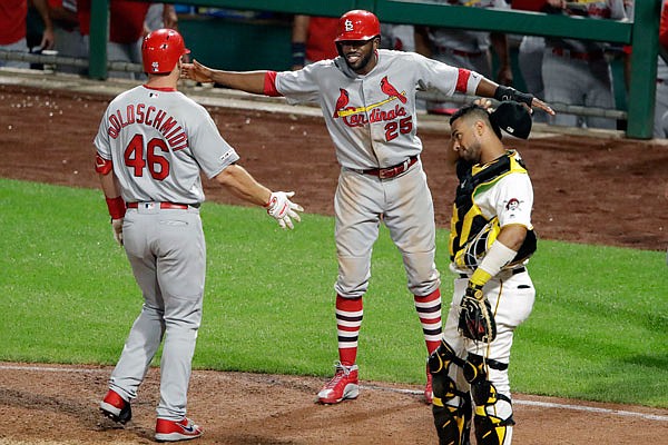 Paul Goldschmidt is greeted by Cardinals teammate Dexter Fowler after hitting a grand slam in the top of the 10th inning Monday night against the Pirates in Pittsburgh. Pirates catcher Elias Diaz looks on.