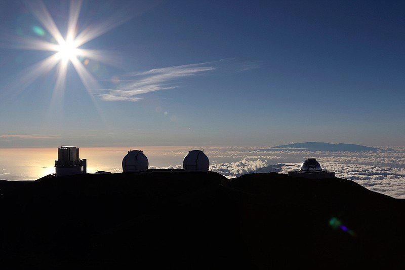 In this Sunday, July 14, 2019, file photo, the sun sets behind telescopes at the summit of Mauna Kea. Scientists are expected to explore fundamental questions about our universe when they use a giant new telescope planned for the summit of Hawaii's tallest mountain. That includes whether there's life outside our solar system and how stars and galaxies formed in the earliest years of the universe. But some Native Hawaiians don't want the Thirty Meter Telescope to be built at Mauna Kea's summit, saying it will further harm a place they consider sacred. (AP Photo/Caleb Jones, File)