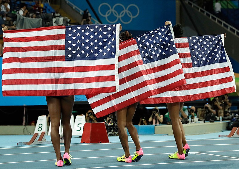 In this Aug. 17, 2016, file photo, gold medal winner Brianna Rollins, center, silver medal winner Nia Ali, left, and bronze medal winner Kristi Castlin, all from the United States, pose with their country's flag after the 100-meter hurdles final during the athletics competitions of the 2016 Summer Olympics at the Olympic stadium in Rio de Janeiro, Brazil. If the Tokyo Olympics were opening today - actually they begin exactly a year from now - the United States would top the overall medal count, and the gold-medal count. That's the forecast released Tuesday, July 22, 2019, by Gracenote Sports, which bills itself as a "sports and entertainment provider" and supplies statistical analysis for sports league around the world. (AP Photo/Matt Dunham, File)