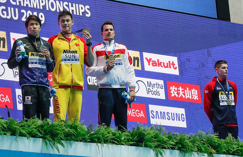 Britain's bronze medalist Duncan Scott, right, refuses to stand with gold medalist China's Sun Yang, second left, as silver winner Japan's Katsuhiro Matsumoto, left, and joint bronze medal winner Russia's Martin Malyutin pose on the podium following the men's 200m freestyle final at the World Swimming Championships in Gwangju, South Korea, Tuesday, July 23, 2019. (AP Photo/Lee Jin-man)