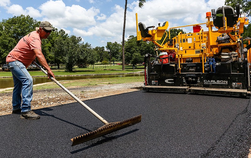 Troy Young from Tri-State Asphalt Inc. smooths out freshly laid asphalt Tuesday on the Spring Lake Park trail in Texarkana, Texas. The project is funded by a Texas Parks and Wildlife Department grant and will include new benches and signs explaining the history of the park.