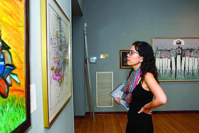 Dr. Injeong Yoon examines artwork at the 31st annual Adult Juried Exhibition at Texarkana Regional Arts Center in Texarkana, Texas. The exhibition is featured throughout all three floors with a total of 116 pieces of art on display.