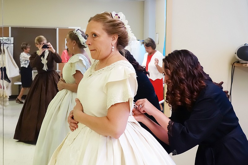 Deby Thompson, left, gets laced layer-by-layer into her recreated 1860s wedding gown. She crafted the piece herself for use in historical reenactments.