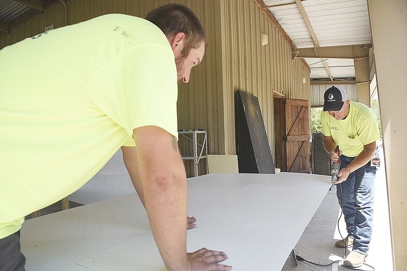 Now that the floodwaters have receded, employees of the Jefferson City Parks, Recreation and Forestry Department are busy repairing park properties, including the pavilion in North Jefferson City, as shown here. Cody Moore, left, holds down the fiber reinforced plastic board while Andrew Bax trims it to size. Although the pavilion is raised, it still had about 4 feet of water in it. Wall coverings had to be removed; stud walls needed pressure washed and treated for mold; damaged wood replaced; and more as they put it back in shape for rentals. 
