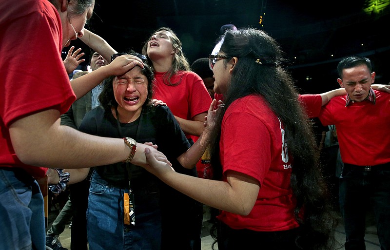 Esperanza Hernandez, of Austin, Texas, is surrounded by members of First Pentecostal Church of Wichita, Kan., as they pray together at the North American Youth Congress at America's Center on Thursday, Aug. 1, 2019, in St. Louis. Praying with Hernandez are Monse Amezuuith, left, Hannah Clark, rear, and Rebecca Martinez. An estimated 36,000 people are attending the gathering presented by United Pentecostal Church International's Youth Ministries team. (Robert Cohen/St. Louis Post-Dispatch via AP)