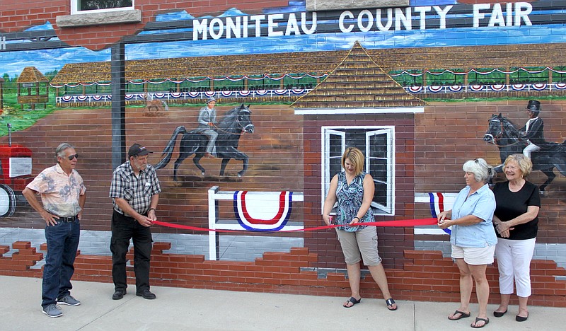 Members of the Moniteau County Historical Society and CPI get ready to officially reveal the Moniteau County Fair mural Aug. 3, 2019, with a ribbon cutting. The completion of the mural stood the test of the elements for nearly ten months, but was at last finished in time for the fair. Shown from left are: Muralist Dennis Holliday, James Albin, Sara Holtsclaw, Ann Grotjan and Ann Albertson.