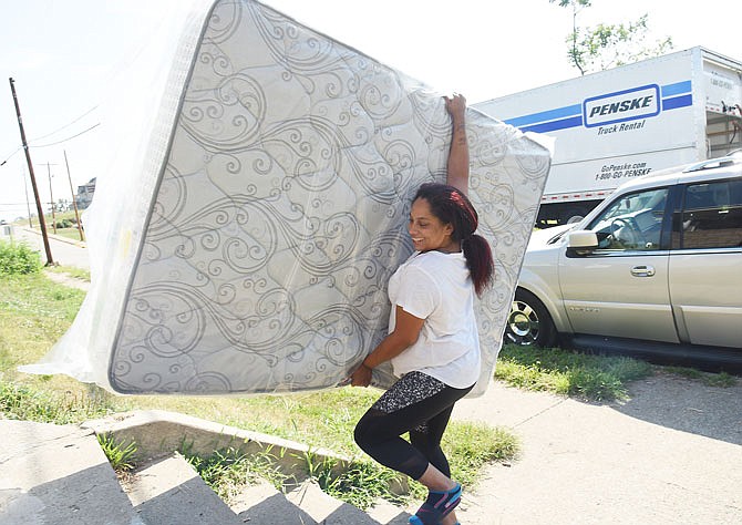 Noya Overman can't help but smile as she carries a new mattress up the steps of her new apartment Tuesday morning. Overman, who has four children, said this is the first time that each child will have their own room. The family, who was displaced by the tornado May 22, formerly lived about a block away in an apartment that was destroyed by the twister.