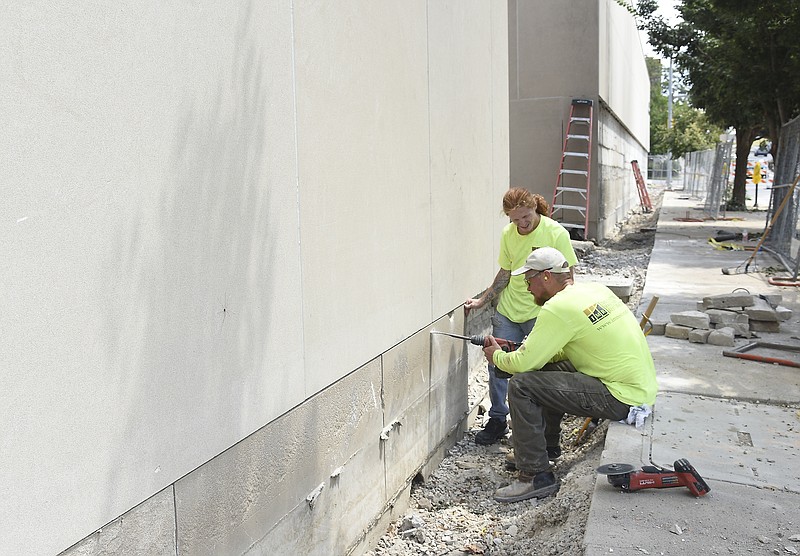 Julie Smith/News Tribune
Tyler Dawson, near, uses a cutting powered chisel to chip away on the limestone panel on the south side of the Truman State Office Building. The material needed replaced in sections so the side that faces E. McCarty Street is getting a makeover, in parts of it. A portion of the sidewalk has been dug up to accomodate the necessary work so it is fenced off and pedestrians are asked to be careful when passing through the area. Next to Dawson is Ian Werle, both of whom work for Innovative Masonry Restoration or IMR. They're part of a large group that has been working on the Truman Building for the last year or more as part of a multi-million dollar restoration and repair project to protect the shell of the building and keep it standing for many more years. Eight-foot limestone panels from the section of wall in the background were removed Monday. 